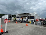 Trailers are parked outside in a parking lot with people walking around in reflective vests.