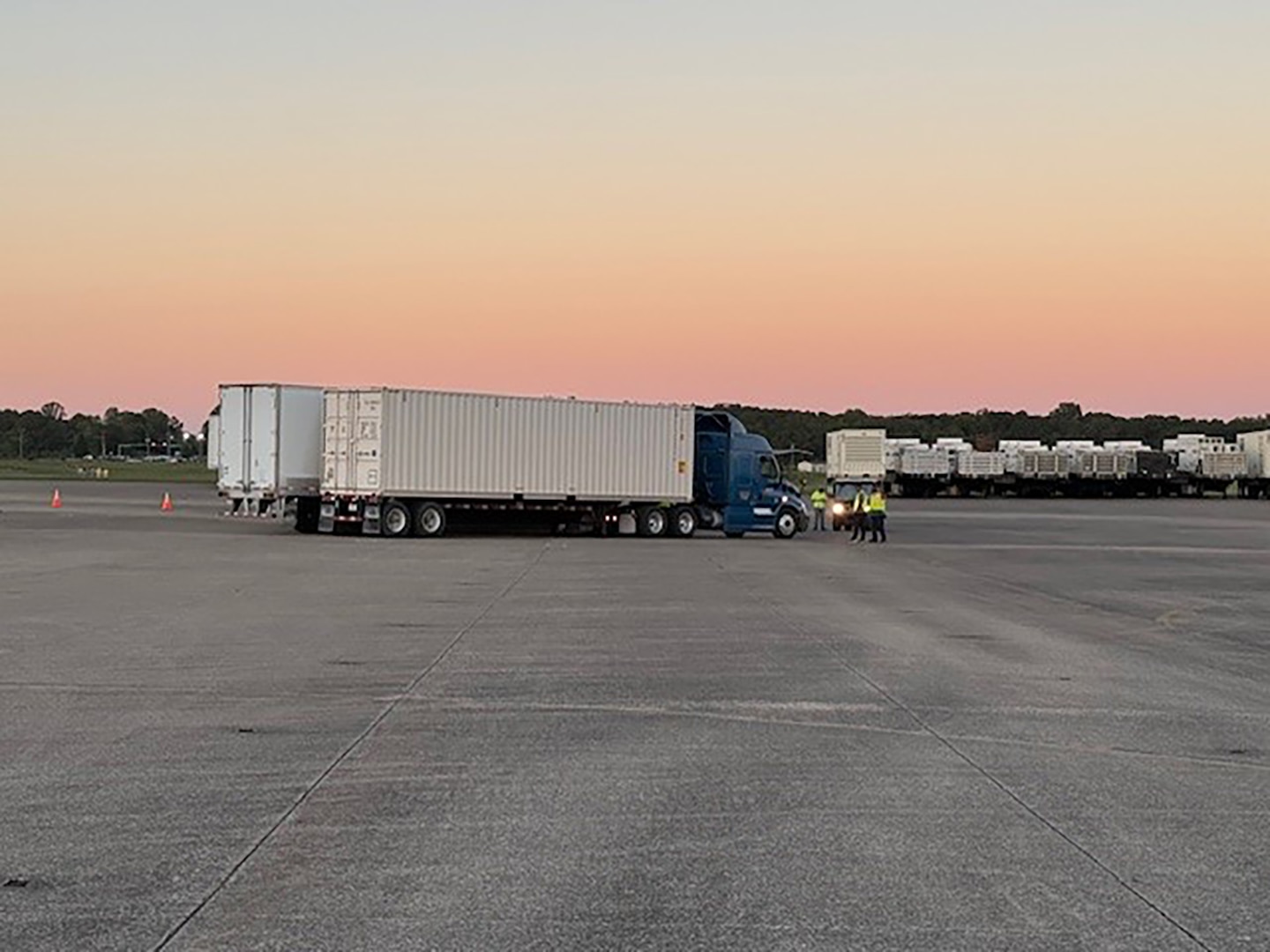 Multiple tractor trailers are parked outside in a large parking lot