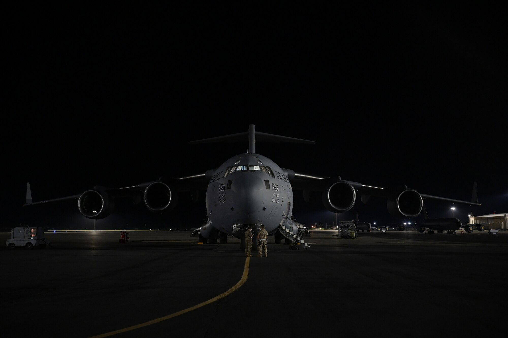 A C-17 Globemaster III aircraft sits on a flightline at night.