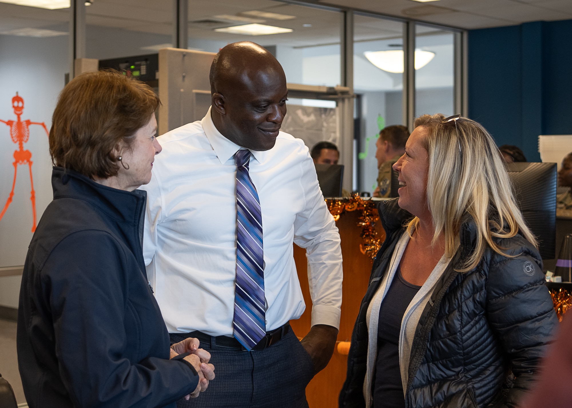 A man speaks to two women in a room.