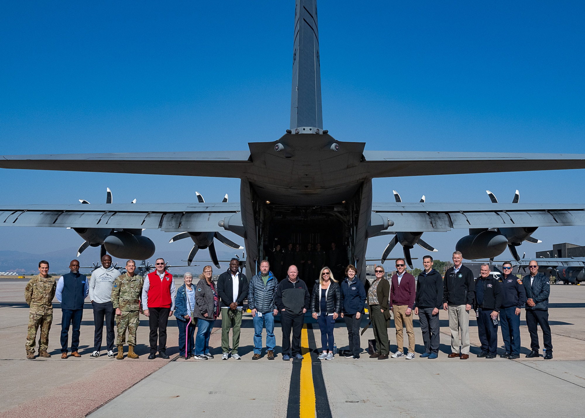 A group of people standing behind a military aircraft.