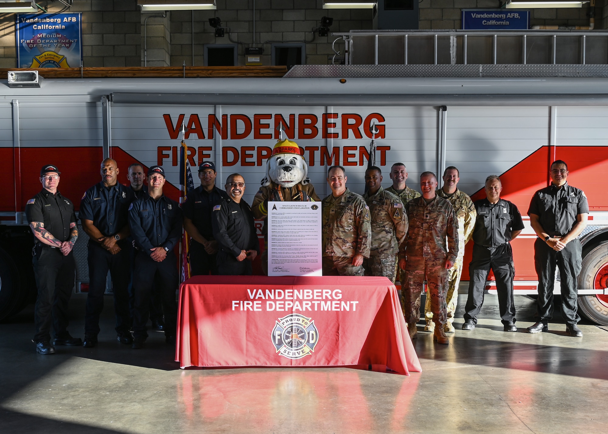 A Space Launch Delta 30 commander (center right), Sparky the Fire Dog (center), and a 30th Civil Engineer Squadron fire chief (center left), along with firehouse staff pose for a photo during the Fire Prevention Week proclamation signing at Vandenberg Space Force Base.
