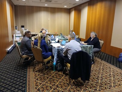 Several people gather in room for discussion.