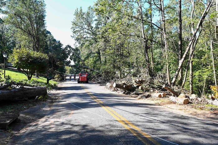 National Guardsmen saw large trees blocking a street.