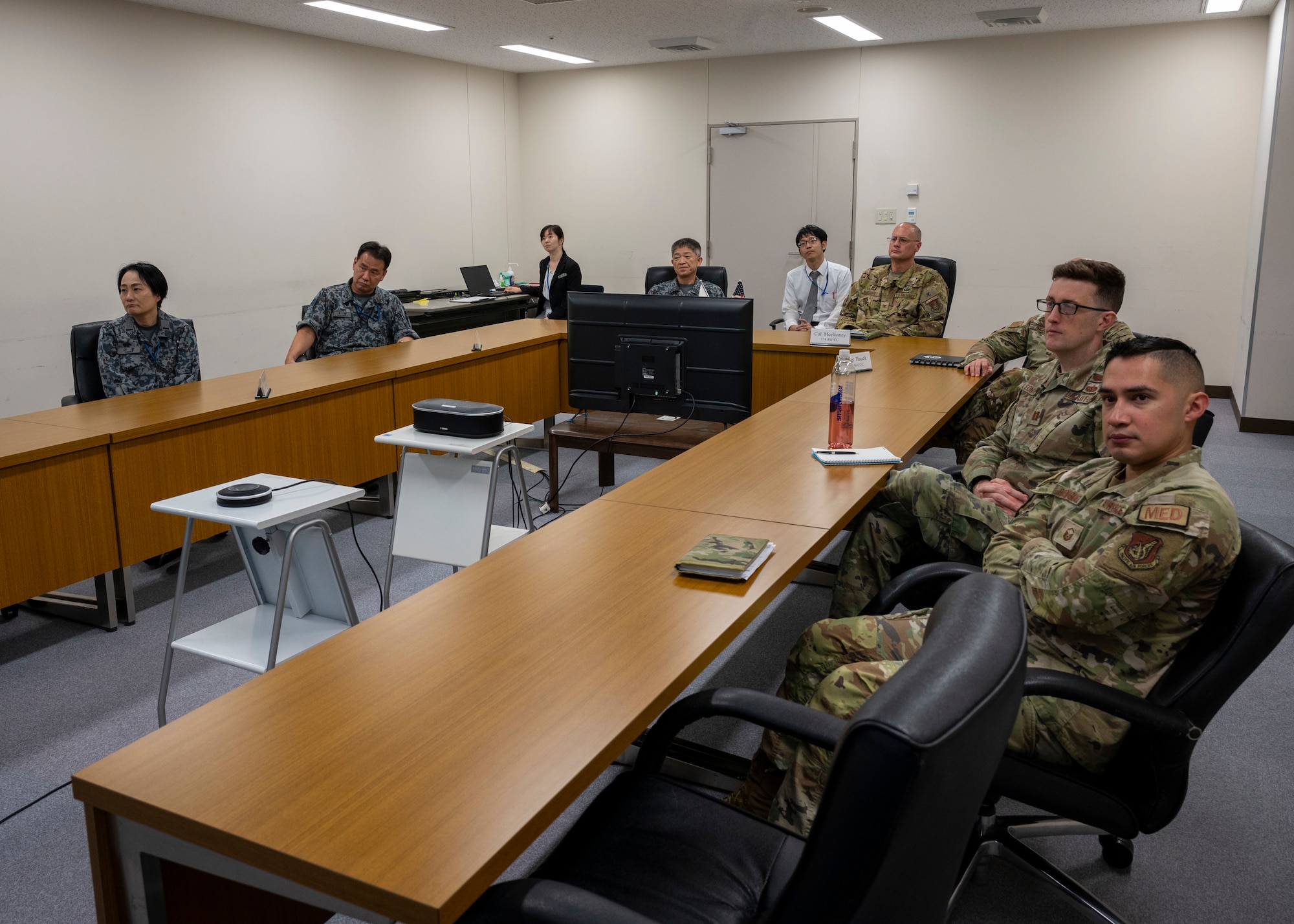 Military members sit around wooden U-shaped tables