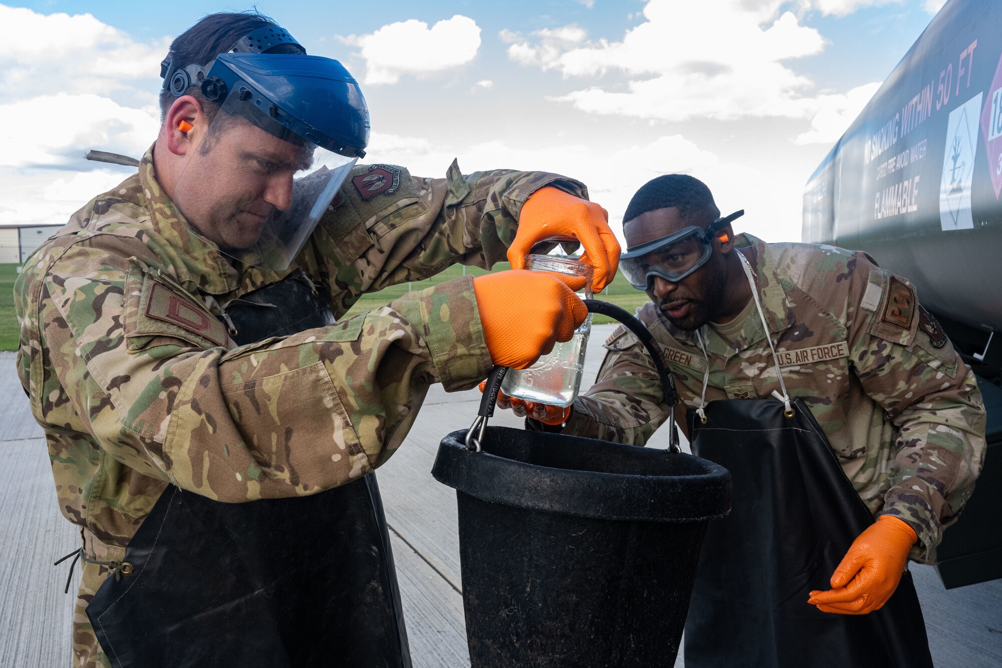 U.S. Air Force Col. Joseph Wall, left, 100th Air Refueling Wing deputy commander, and Senior Airman Jovon Green, 100th Logistics Readiness Squadron fuels facility technician, look at a water sample collected from a mobile refueling truck during a operations check at Royal Air Force Mildenhall, England, Oct. 4, 2024.