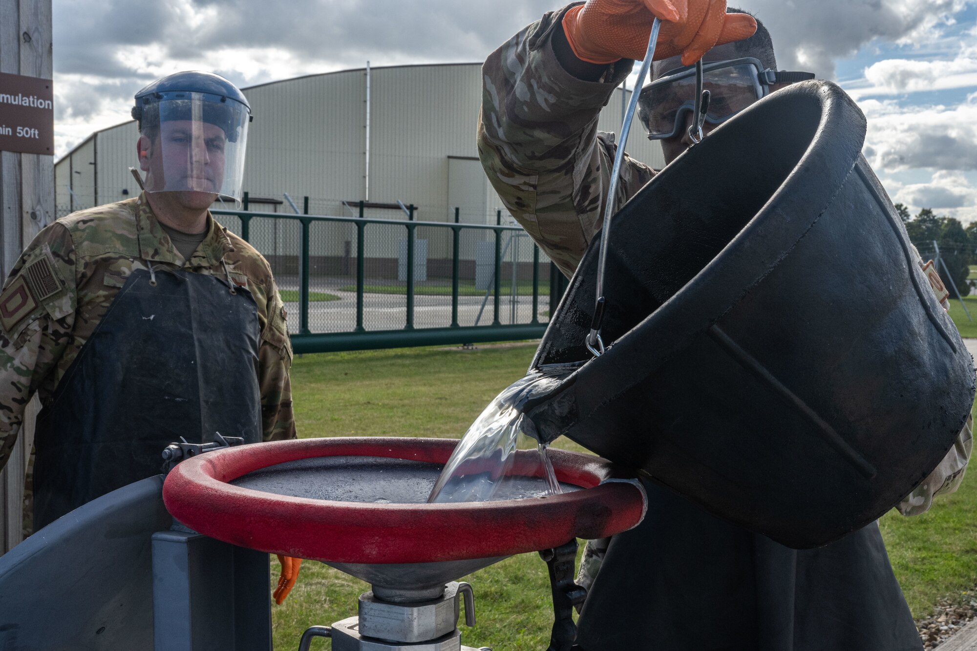 U.S. Air Force Senior Airman Jovon Green, right, 100th Logistics Readiness Squadron fuels facility technician, pours water collected from a mobile refueling truck into a bowser at Royal Air Force Mildenhall, England, Oct. 4, 2024.