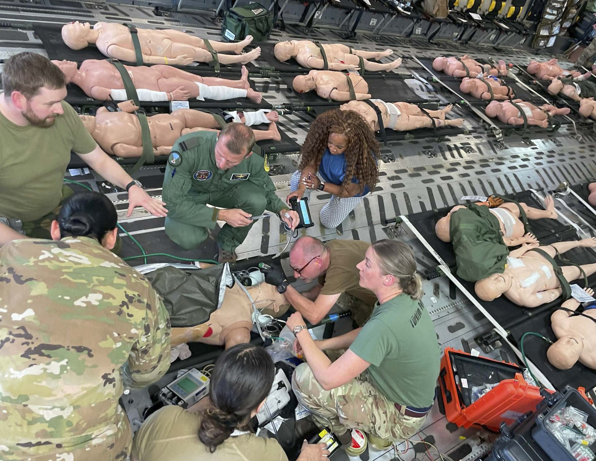 A physician simulated intubates a mannequin during an exercise with other physicians on an aircraft.