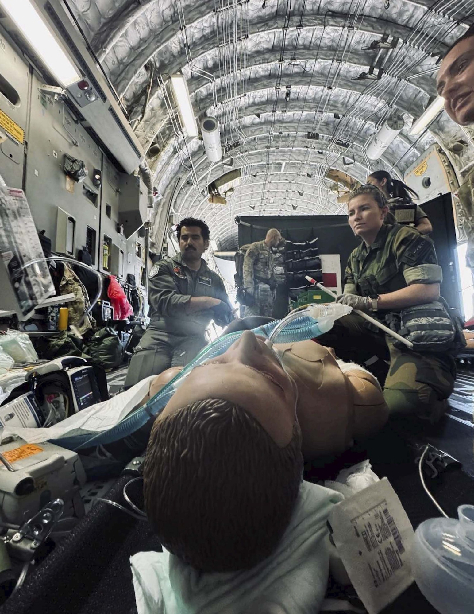 Two physicians prepare to put a chest tube into a simulated patient on an aircraft.