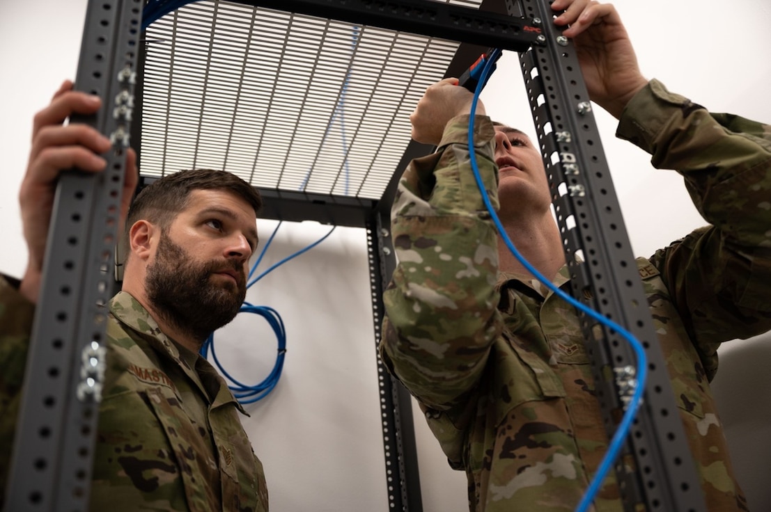 U.S. Air Force Tech. Sgt. William Lamastro, 633d Communications Squadron cable & antenna maintenance, left, watches as U.S. Airman 1st Class Terrance Butler, 633d CS client systems technician, right, connects the cable to the extension cord at Joint Base Langley-Eustis, Virginia, Sept. 11, 2024. Butler was being tested on his knowledge of connecting cables to ensure he would be able to set up networks in the future.  (U.S. Air Force Photo by Airman Donnell Ramsey)