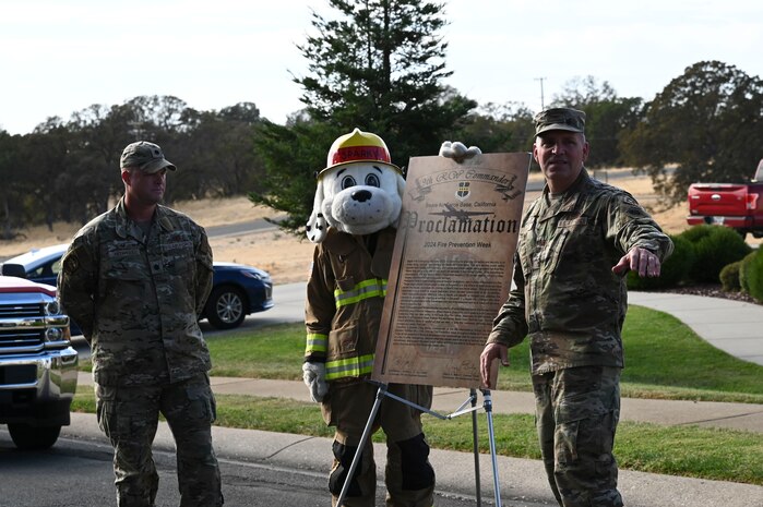 U.S. Air Force Col. Craig Bailey, 9th Maintenance Group commander, speaks to Beale's firefighters alongside Sparky the Dog, and Lt. Col. Brennan Howell, 9th Civil Engineer Squadron commander, at the proclamation signing of Fire Prevention Week at Beale Air Force Base, California, Oct. 6, 2024.