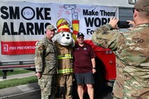 U.S. Air Force Lt. Col. Brennan Howell, 9th Civil Engineer Squadron commander, Sparky the Dog, and Gary Bradford, District 4 Supervisor, Yuba County, pose for a photo during the Fire Prevention Week kick off at Beale Air Force Base, California, Oct. 6, 2024.