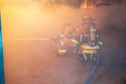 Image of two fire fighters spraying fire hose.