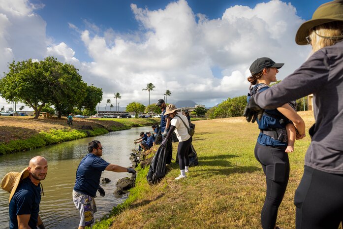 Event volunteers with Nan, Inc., a construction company, remove debris during a Mokapu Central Drainage Channel cleanup, Marine Corps Base Hawaii, Sept. 28, 2024. The volunteer event contributed in protecting an important wildlife habitat through flood mitigation measures. (U.S. Marine Corps photo by Lance Cpl. Marcos AlbertoRocha)