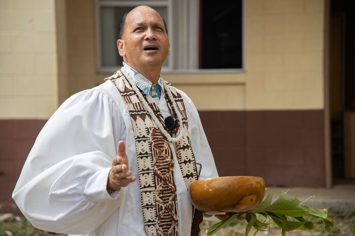 Kahu Kordell Kekoa, a Hawaiian priest with Kahu Kekoas Ministerial Services, chants a pule, a Hawaiian prayer, during a traditional Hawaiian blessing ceremony for Mackie Hall to U.S. Marine Corps Col. Jeremy Beaven, commanding officer of Marine Corps Base Hawaii, and the project team at MCBH, Sept. 30, 2024. The ceremony demonstrated respect and honor for the land and united the project team in anticipation of the demolition of Mackie Hall, one of several military construction plans in line with Barracks 2030, a Marine Corps initiative to improve the quality of life of Marines through the modernization of facilities and the professionalization of barracks management. (U.S. Marine Corps photo by Sgt. Julian Elliott-Drouin)