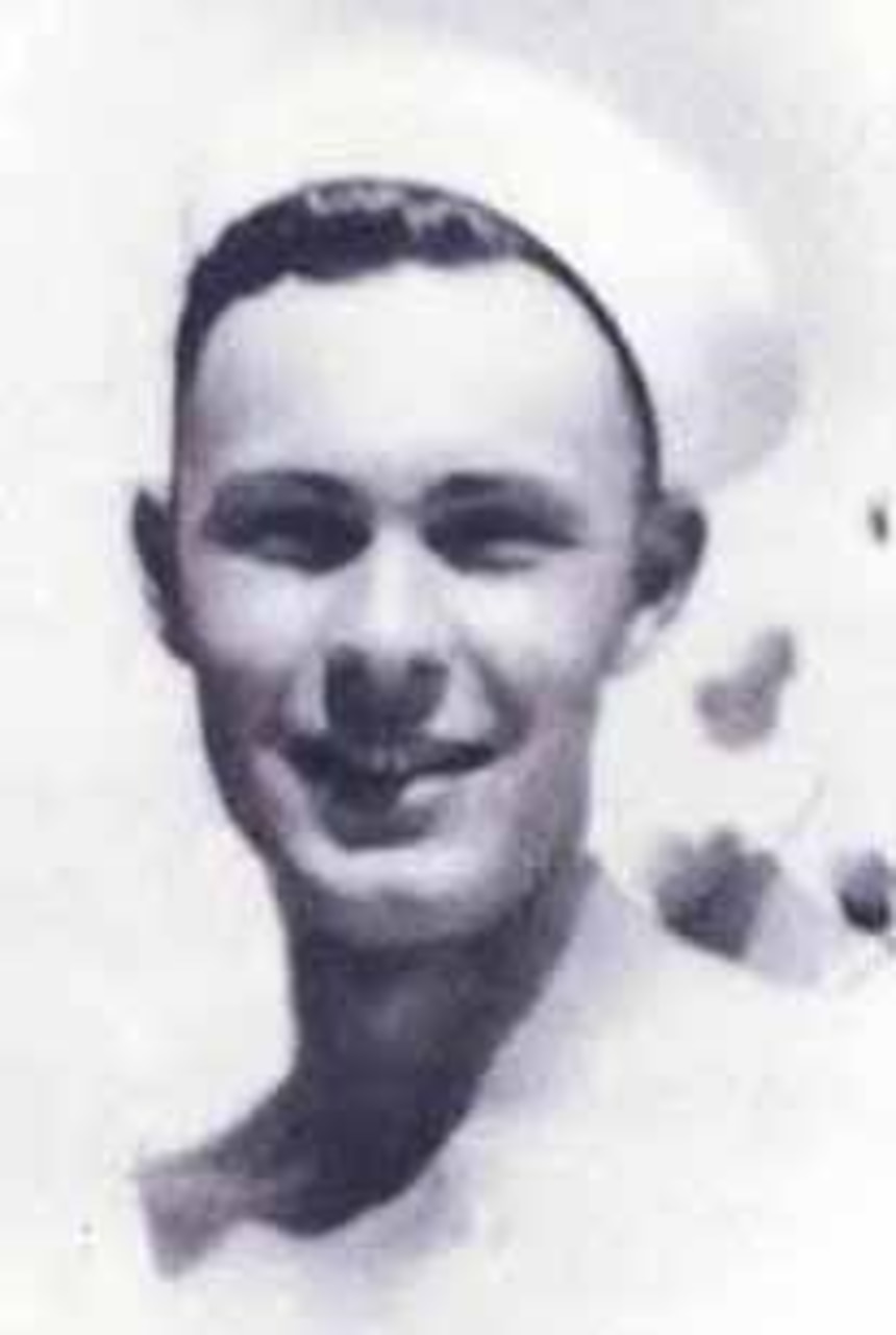 A sailor in uniform poses for a photo.