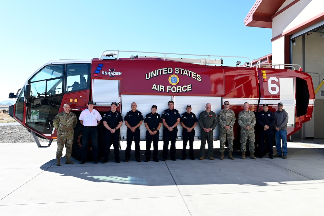 Firefighters and EMS personnel stand in front of fire engine.