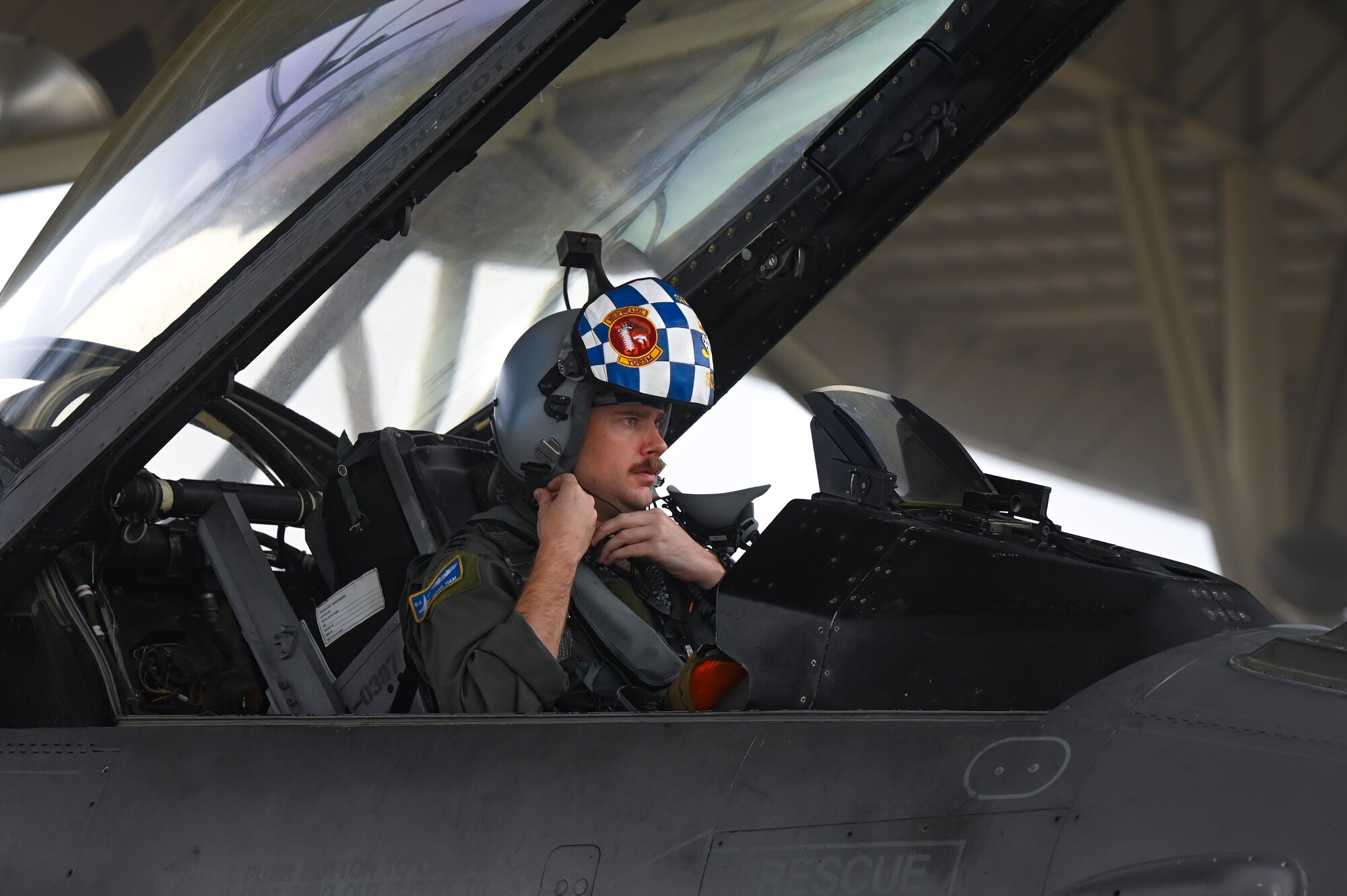 Pilot adjusting helmet while in the jet.