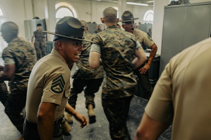 U.S. Marine Corps Staff Sgt. Enrique Dominguez III, an instructor with Marine Corps Recruit Depot San Diego Drill Instructor School, Recruit Training Regiment, directs the new Marines of DI school class 1-25 into a squad bay at Marine Corps Recruit Depot San Diego, California, Oct. 3, 2024. DI school develops leadership, command presence, instructional ability, physical fitness, and professional knowledge in officers and noncommissioned officers to prepare them for the duties of a drill instructor.  (U.S. Marine Corps photo by Sgt. Jesse K. Carter-Powell)
