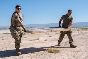 U.S. Air Force Tech. Sgt. Brianna Gonzales, 635th Materiel Maintenance Squadron regional training noncommissioned officer in charge, left, and U.S. Air Force Tech. Sgt. Joseph Farmer, 635th MMS electrical systems supervisor, moves a solar panel during Operation TRAILBLAZER at Holloman Air Force Base, New Mexico, Oct. 1, 2024.