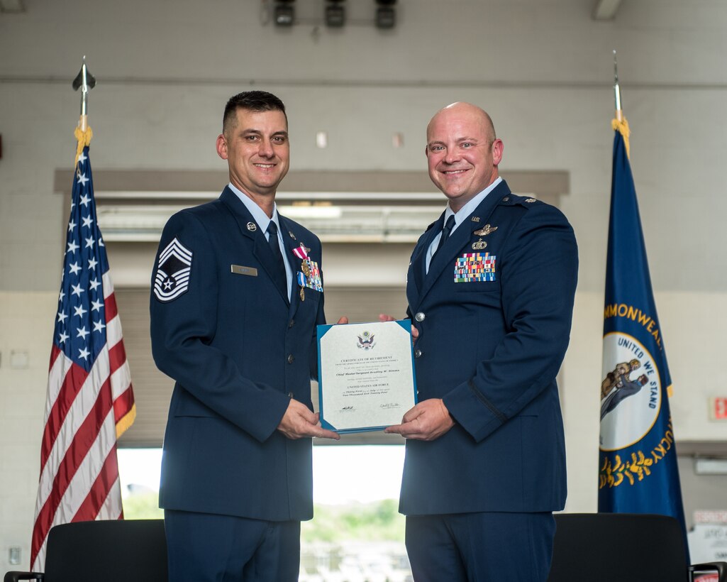 Lt. Col. Josh Ketterer, right, commander of the 165th Airlift Squadron, presents a Certificate of Retirement to Chief Master Sgt. Bradley Simms, a loadmaster and the squadron’s senior enlisted leader, during Simms’ retirement ceremony at the Kentucky Air National Guard Base in Louisville, Ky., July 20, 2024. Simms retired from the 123rd Airlift Wing after more than 27 years in the military. (U.S. Air National Guard photo by Airman 1st Class Annaliese Billings)