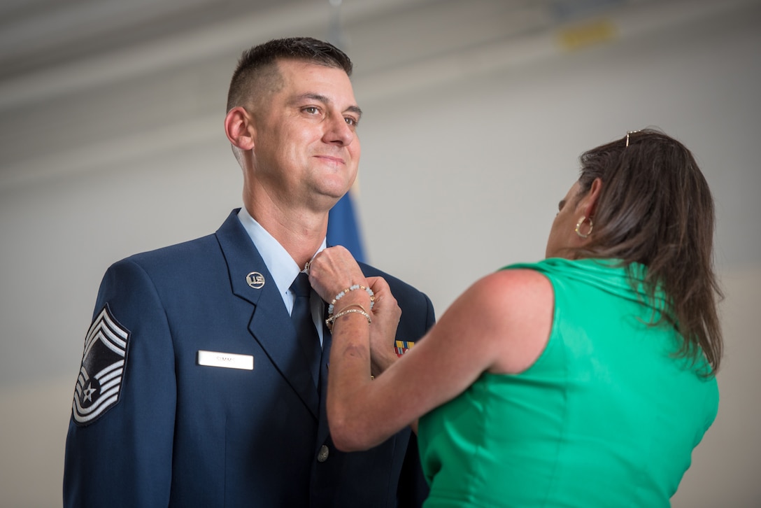 Chief Master Sgt. Bradley Simms, a loadmaster and senior enlisted leader for the 165th Airlift Squadron, has a retirement pin placed on his uniform by his wife during a ceremony at the Kentucky Air National Guard Base in Louisville, Ky., July 20, 2024. Simms retired with more than 27 years of military service. (U.S. Air National Guard photo by Airman 1st Class Annaliese Billings)