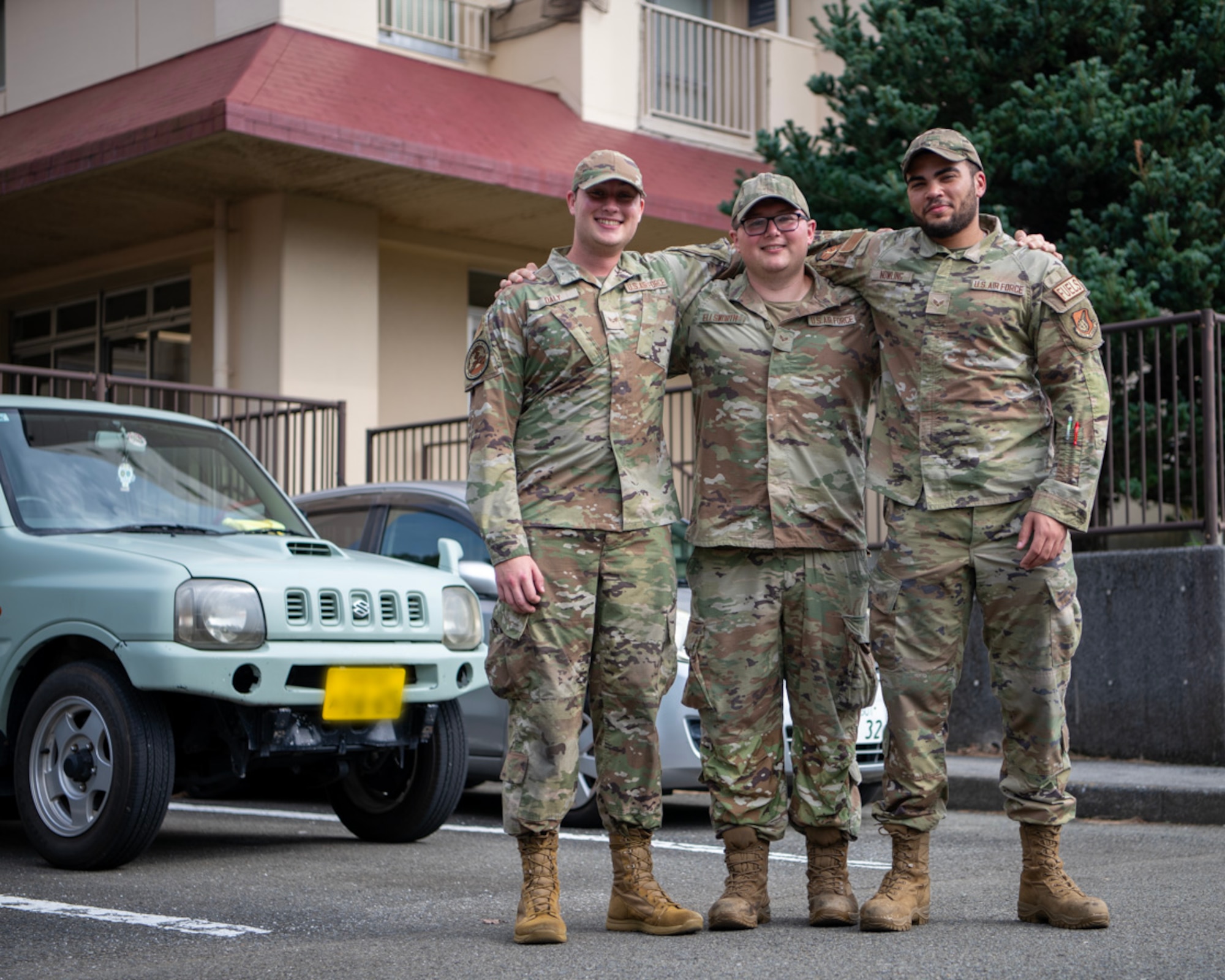 Three military members pose arm in arm for a photo.
