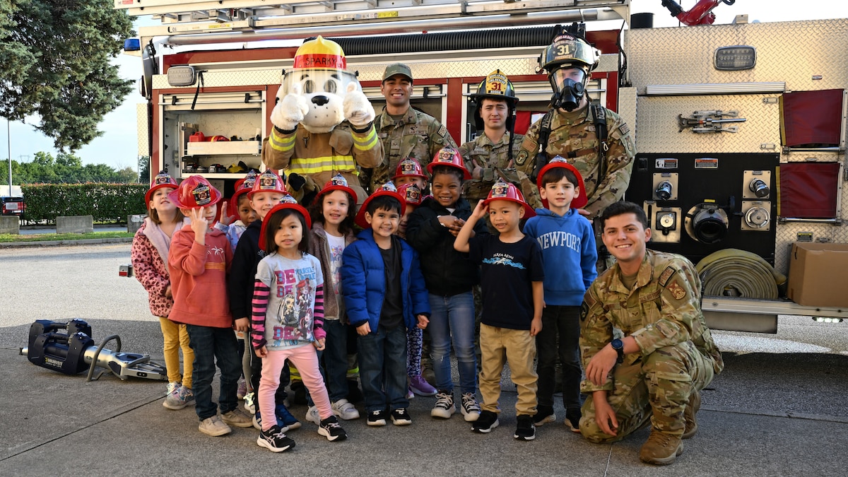 A group photo of children, firefighters, and a fire dog mascot