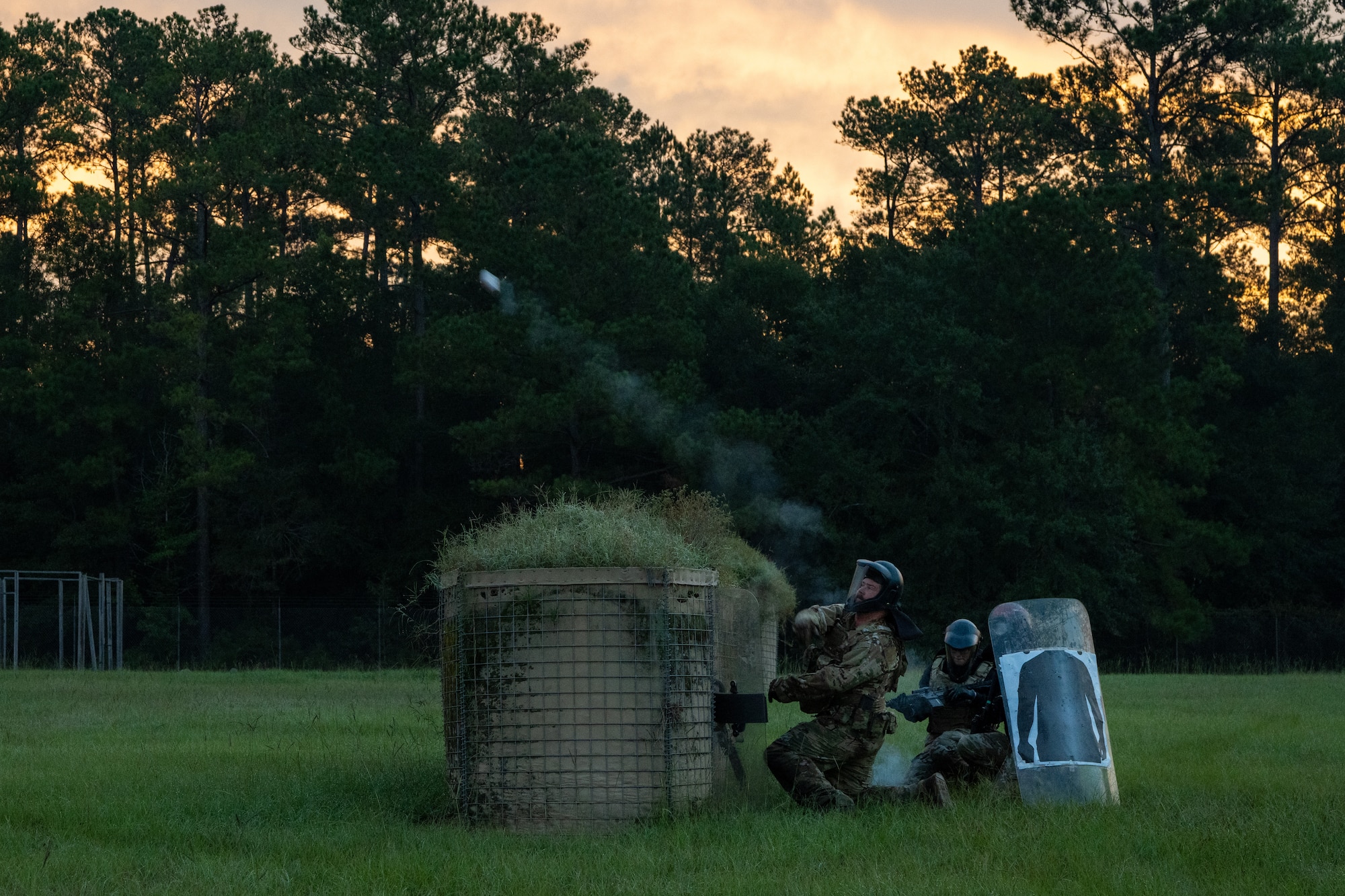 An Airman throws a smoke grenade