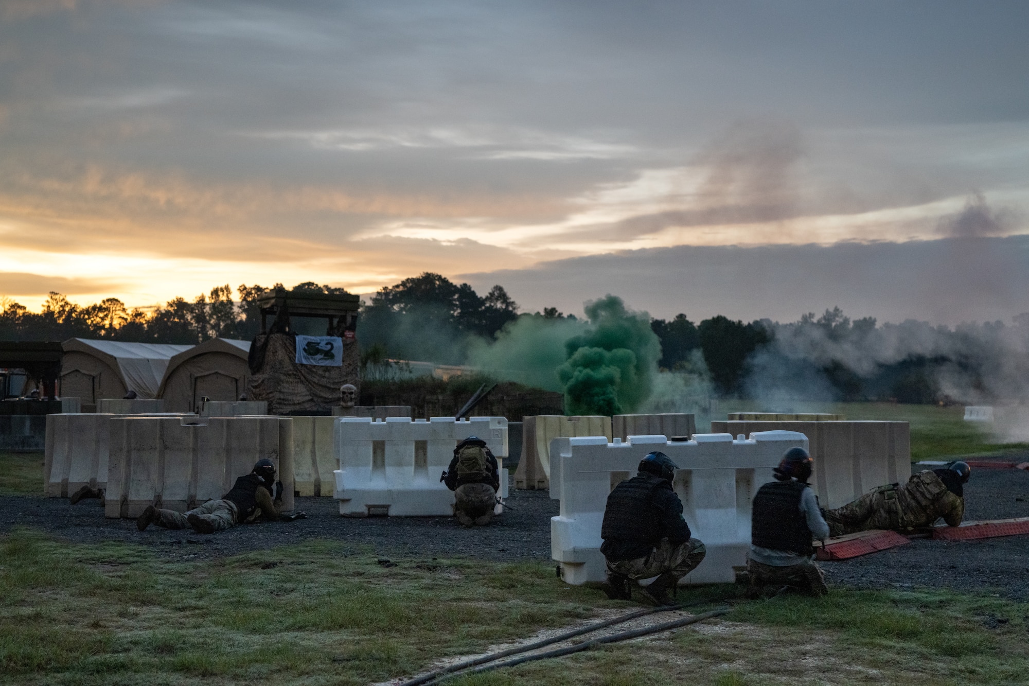 A group of Airmen conduct a simulated base assault