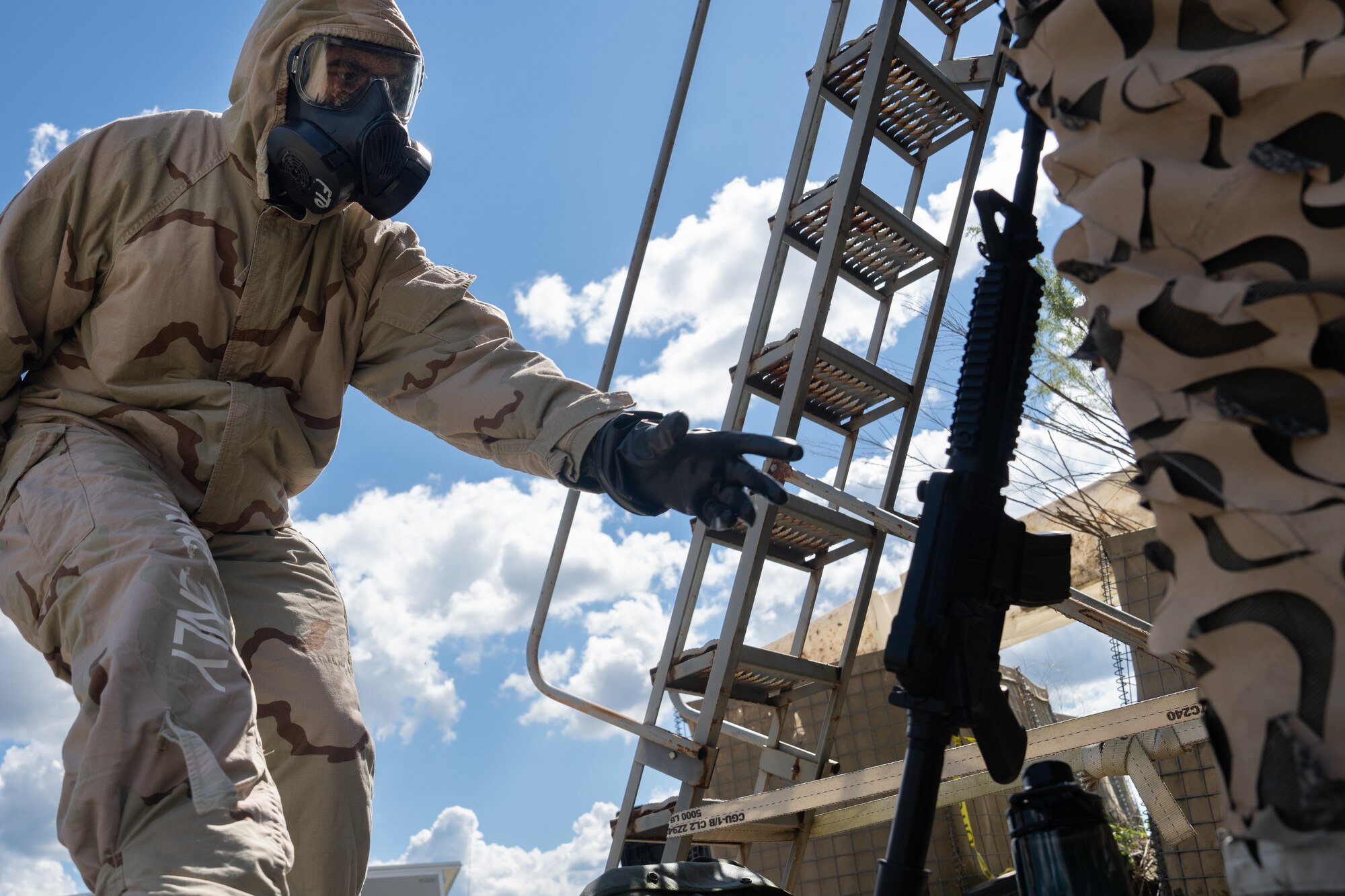 An Airman reaches for a rifle