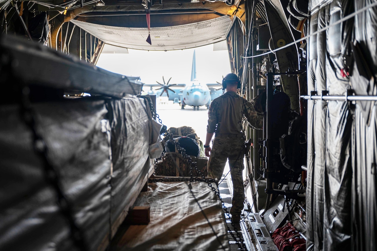 An airman performs preflight checks on cargo inside a military aircraft.
