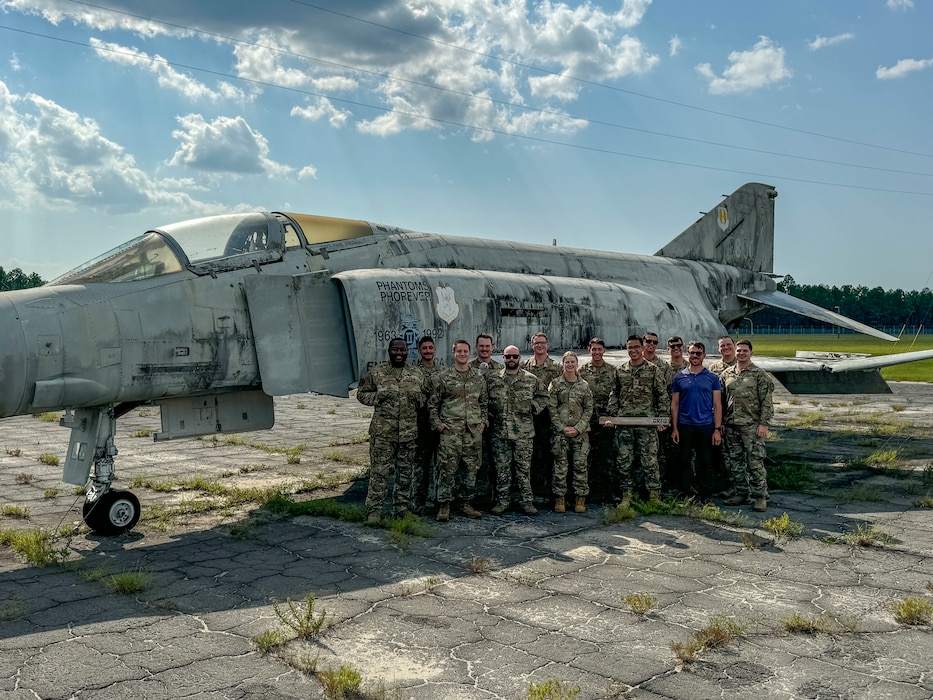 The Beale Air Force Base Combat Innovation Exercise Team poses for a photo next to a decommissioned McDonnell Douglas F-4 Phantom II at after successfully completing two week of Innovation training and Combat Innovation scenarios Eglin Air Force Base, Florida, Aug. 8, 2024.