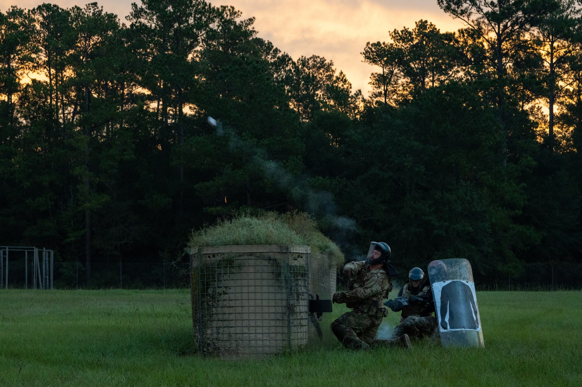 An Airman throws a smoke grenade