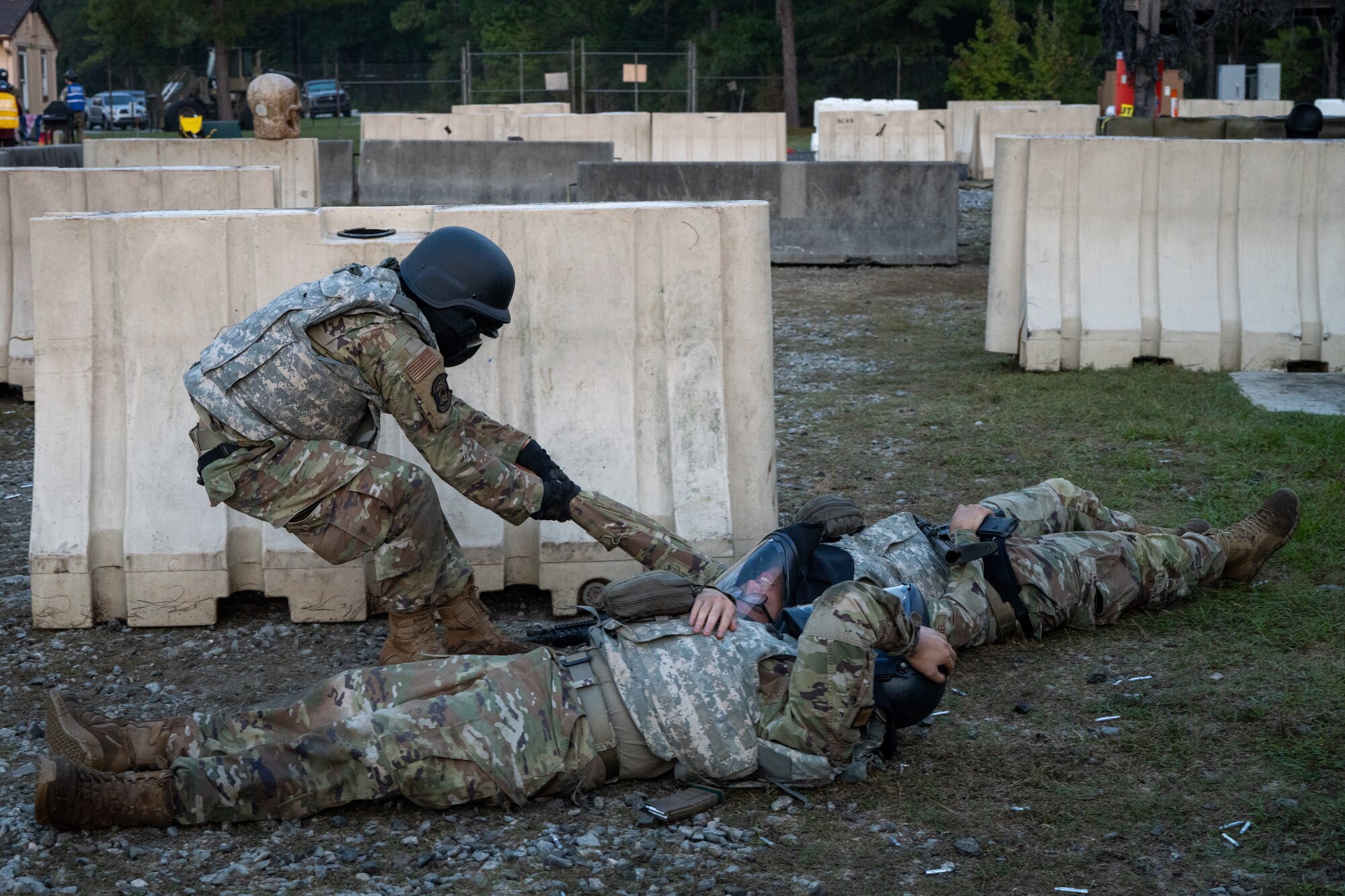 An Airman pulls simulated casualties behind cover