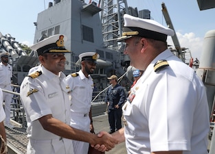 Cmdr. Nicholas Maruca, right, commanding officer of the USS Dewey (DDG 105), greets Indian navy Cmdr. Swapnil Srivastava on Dewey’s quarterdeck after arriving in Visakhapatnam, India for Exercise Malabar 2024.