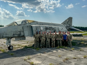 The Beale Air Force Base Combat Innovation Exercise Team poses for a photo next to a decommissioned McDonnell Douglas F-4 Phantom II at after successfully completing two week of Innovation training and Combat Innovation scenarios Eglin Air Force Base, Florida, Aug. 8, 2024.