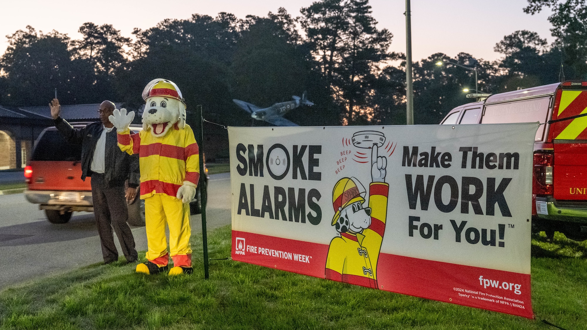 Eric Harper, 4th Civil Engineer Squadron assistant fire chief, and Sparky the dog, fire prevention mascot, greet base personnel during 2024 Fire Prevention Week at Seymour Johnson Air Force Base, North Carolina, Oct. 7, 2024. The theme for 2024 Fire Prevention Week stresses the importance of having a functional smoke alarm to increase the chance of survival during a house fire. (U.S. Air Force photo by Airman 1st Class Rebecca Tierney)