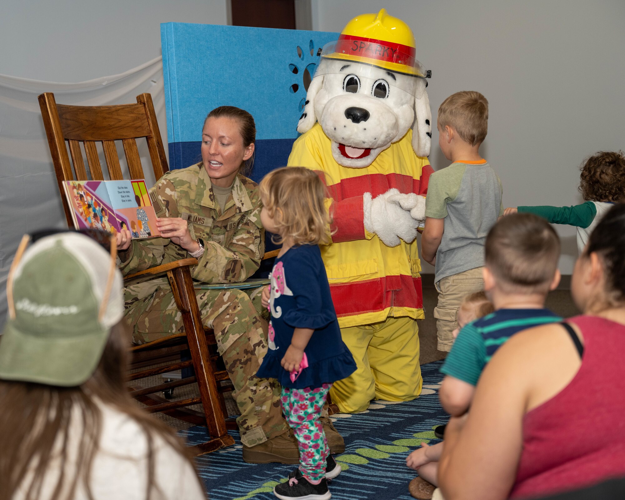 U.S. Air Force Airman 1st Class Sophia Williams, 4th Civil Engineer Squadron driver and operator, and Sparky the dog, fire prevention mascot, read to children at the base library during 2024 Fire Prevention Week at Seymour Johnson Air Force Base, North Carolina, Oct. 7, 2024. The theme for 2024 Fire Prevention Week stresses the importance of having a functional smoke alarm to increase the chance of survival during a house fire. (U.S. Air Force photo by Airman 1st Class Rebecca Tierney)
