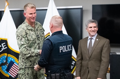 A Navy officer in camouflage shakes hands with a police officer