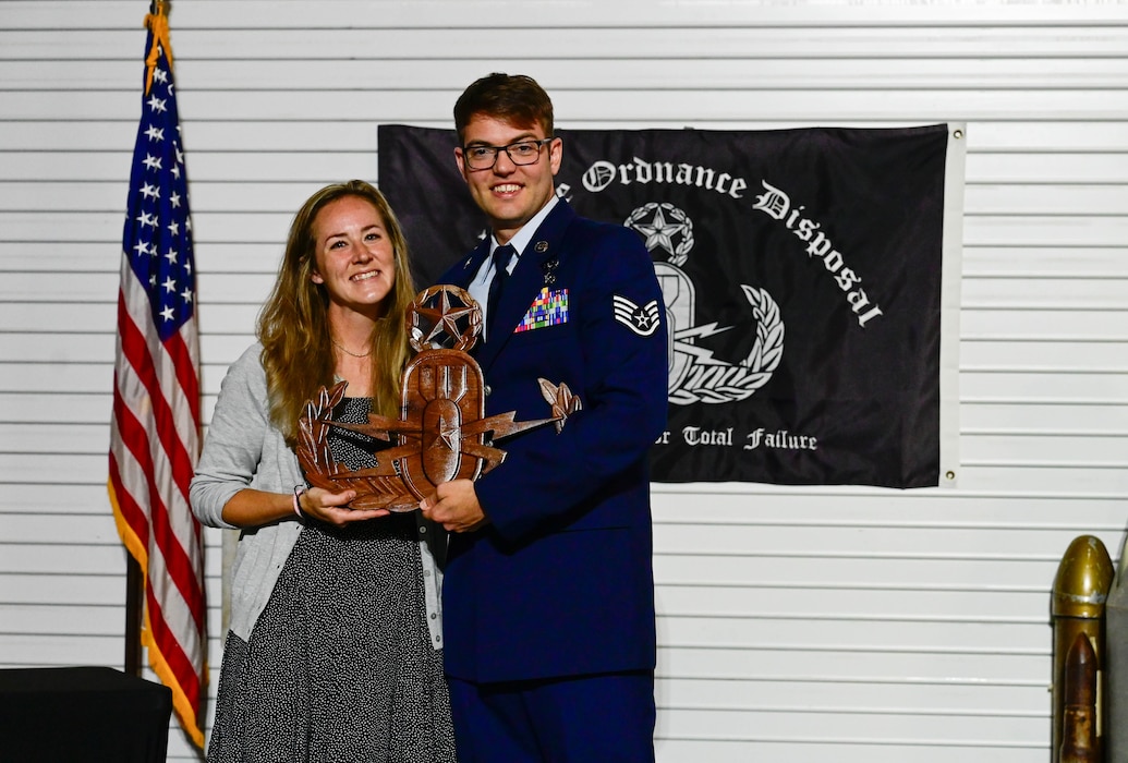 Staff Sgt. Ian Miller, 19th Civil Engineer explosive ordnance disposal (EOD) technician, right, and Abbie Miller, spouse, left, display a “Master Badge” award for his time and efforts in service at Little Rock Air Force Base, Arkansas, Oct. 7, 2024. Throughout Miller’s career he has honed skills through hours of training, improving his procedures and leadership philosophy.