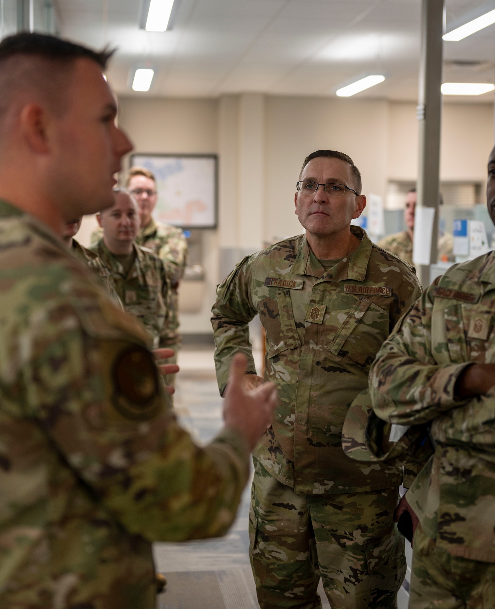 Chief Master Sgt. Travis Chadick, Air Force Nuclear Weapons Center command chief (center), listens during a briefing with Airmen from the 91st Maintenance Group at Minot Air Force Base, North Dakota, Oct. 4, 2024. The visit provided an opportunity for Chadick to discuss readiness and the vital role of maintenance personnel in supporting the nuclear deterrence mission. (U.S. Air Force photo by Airman 1st Class Luis Gomez)