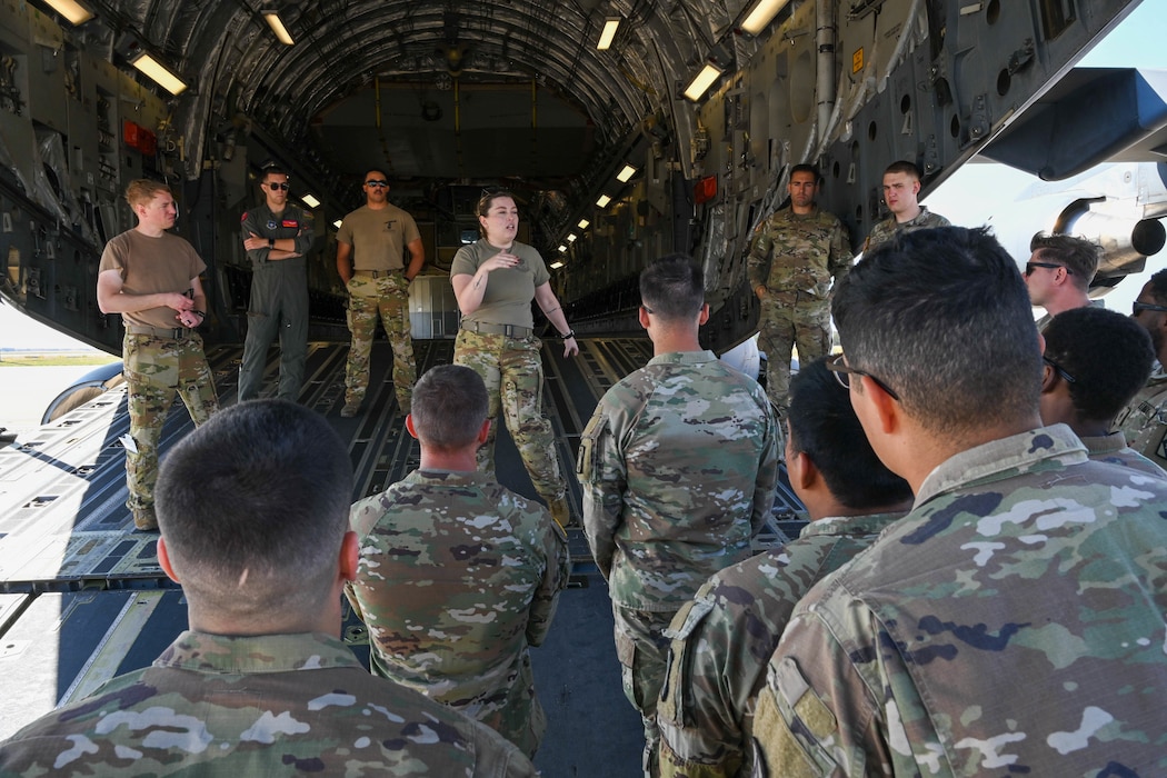 U.S. Air Force Staff Sgt. Georgia Yessis, 58th Airlift Squadron (AS) instructor loadmaster, explains the process of performing an upload on a C-17 Globemaster III aircraft to Soldiers from Fort Sill, Oklahoma, at Altus Air Force Base, Oklahoma, Oct. 7, 2024. After uploading multiple tactical vehicles, 58th AS instructor loadmasters demonstrated to the Soldiers how to secure cargo for flight. (U.S. Air Force photo by Senior Airman Miyah Gray)