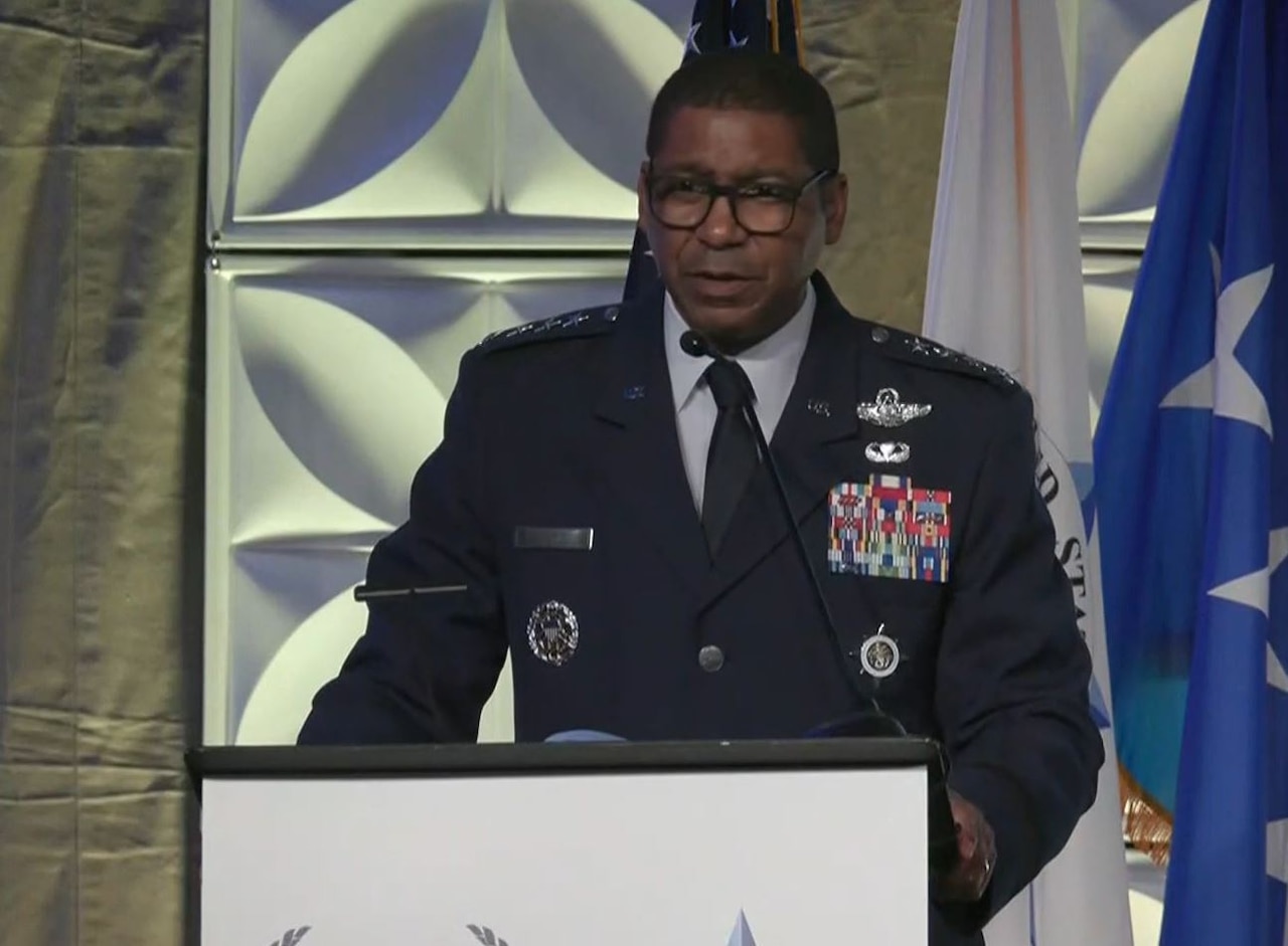 A man in a dress military uniform with four stars on each shoulder stands at a podium looking forward into the camera.