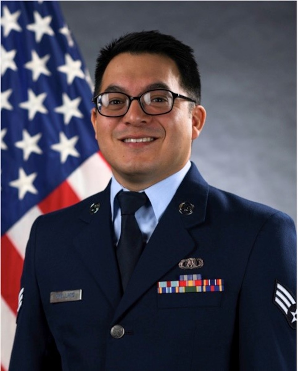 Official photo of SrA Christopher Arellano, guitarist with the USAF Band of the Pacific, Yokota AB, Japan.  SrA Arellano is wearing blue service dress in front of the American flag.