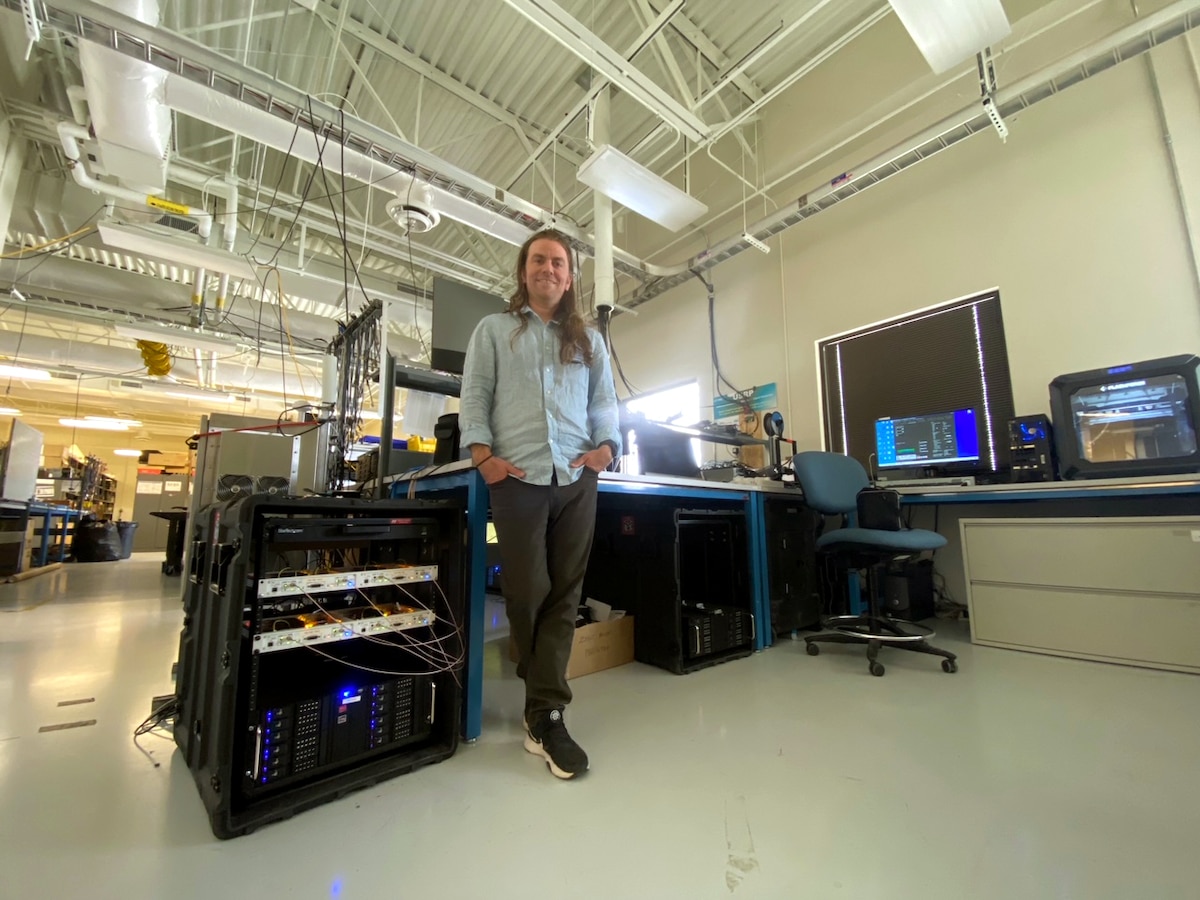 Man poses for photo in front of desk in a laboratory setting