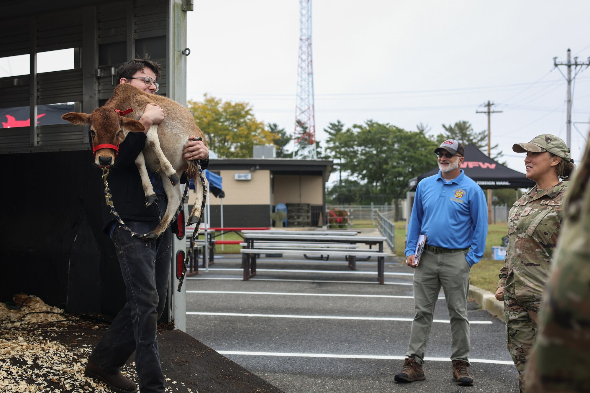 From right, U.S. Air Force Tech. Sgt. Marie Madara, 177th Security Forces Squadron command support staff member and Mr. Jonathan Hinker, New Jersey Veterans of Foreign Wars senior vice commander - Army, witness Mr. Collon Meyers carrying a calf owned by Mrs. Annamarie Daniecki, during Community Assessment and Resiliency Engagement (CARE) Day at the 177th Fighter Wing, Egg Harbor Township, New Jersey, Sept. 27, 2024. CARE day is a program in which members of the 177th FW can come together to celebrate community and new partnerships. (U.S. Air National Guard photo by Airman 1st Class Connor Taggart)