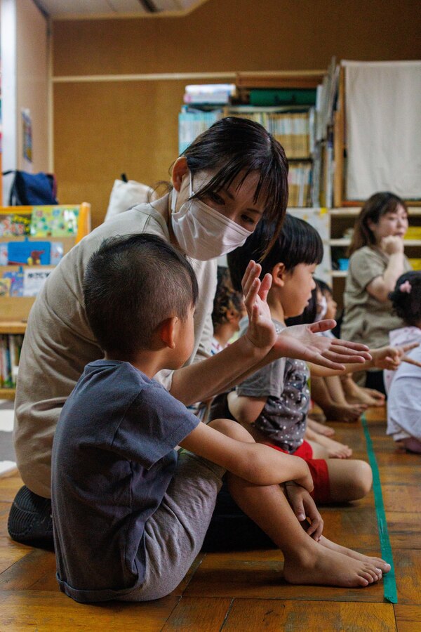 A preschool teacher translates for a volunteer during a community relations event at Ekimae Hoikuen in Iwakuni, August 8, 2024. Volunteers from MCAS Iwakuni visit local preschools in Iwakuni to foster a healthy and positive relationship between base personnel and the local community. The children were introduced to “Head, Shoulders, Knees and Toes” before playing “Duck, Duck, Goose” with the volunteers. (U.S. Marine Corps photo by Lance Cpl. David Getz)
