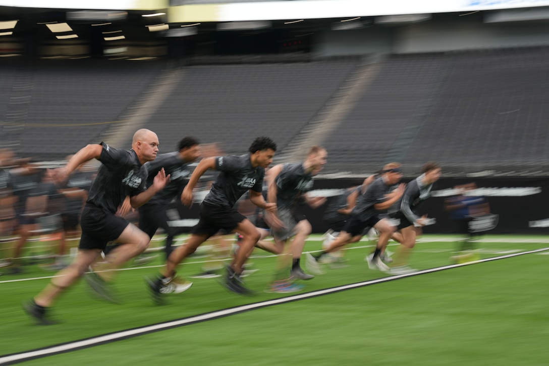 A group of airmen run together in a sports stadium in a photo using a blurred effect.