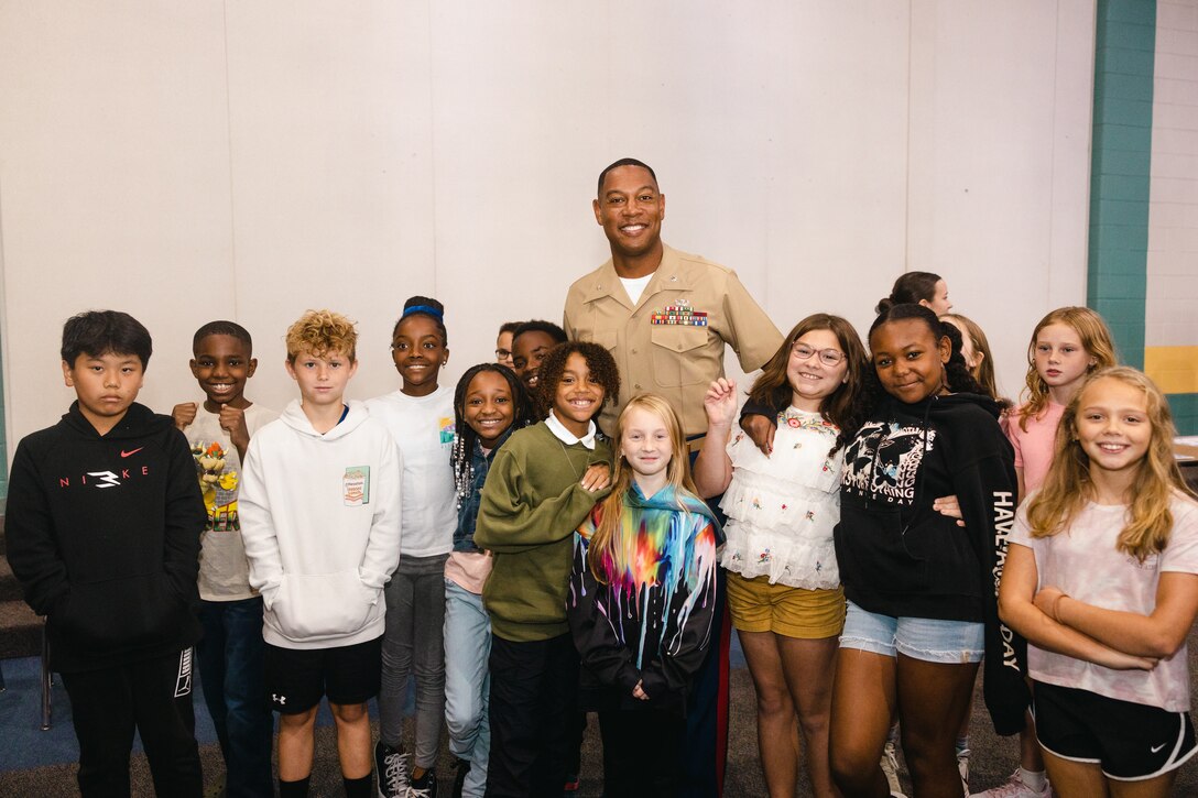 U.S. Marine Corps Lt. Col. Anthony M. Ansley II, left, commanding officer of Combat Logistics Battalion 22, Combat Logistics Regiment 27, 2nd Marine Logistics Group, and students with Carolina Forest International Elementary School, pose for a group photo during a CLB-22 adopt-a-school event at Carolina Forest International Elementary School, in Jacksonville, North Carolina, Oct. 2, 2024. CLB-22 signed a Proclamation of Adoption Partnership with Carolina Forest International Elementary School to strengthen the relationship between Marines and the students through volunteering and mentorship. (U.S. Marine Corps photo by Sgt. Mary Kohlmann)